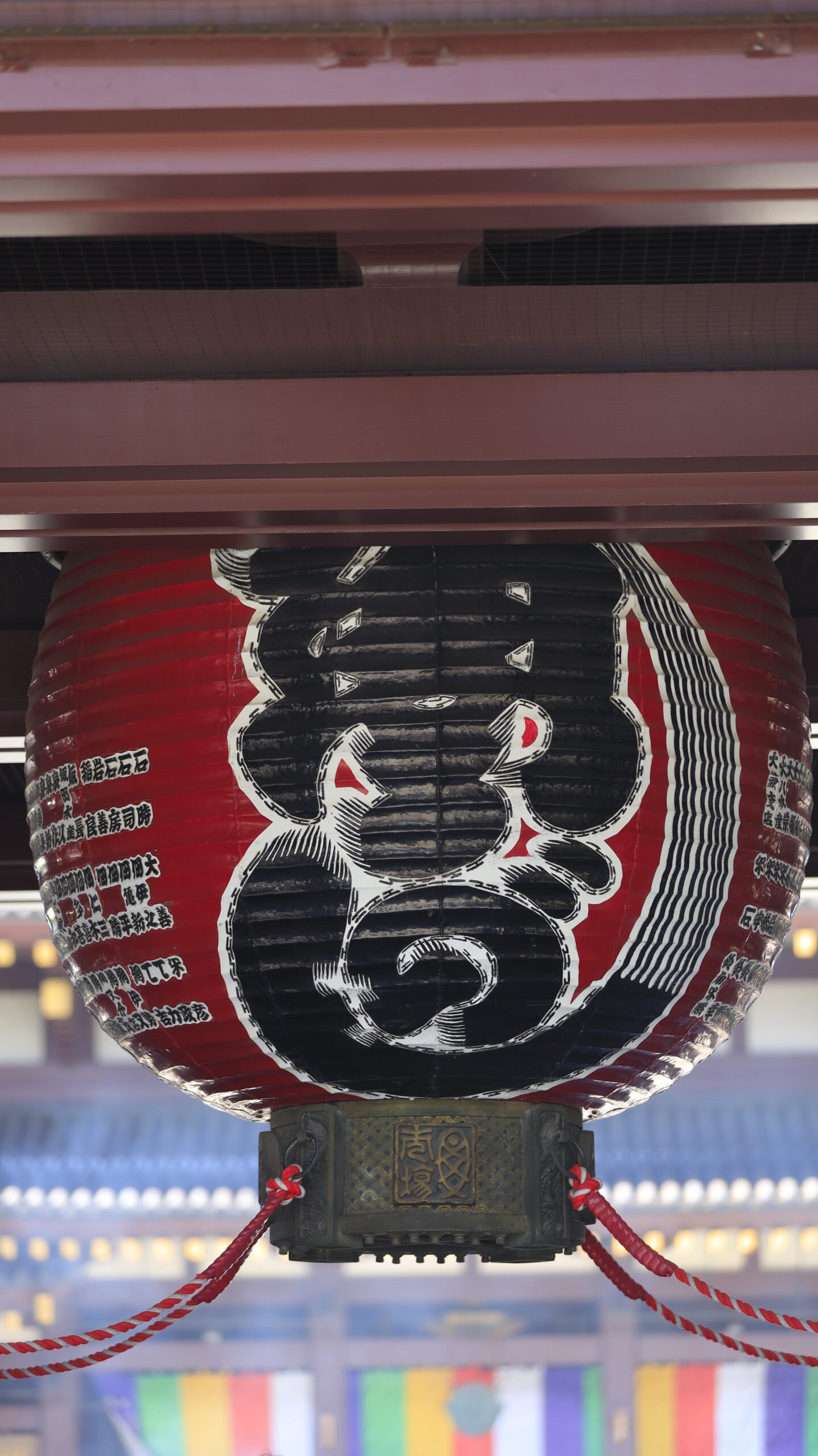 川崎大師の風鈴市で大きな提灯と奥にある本堂を一緒に収め、祭りと寺院の風景を融合させた写真。