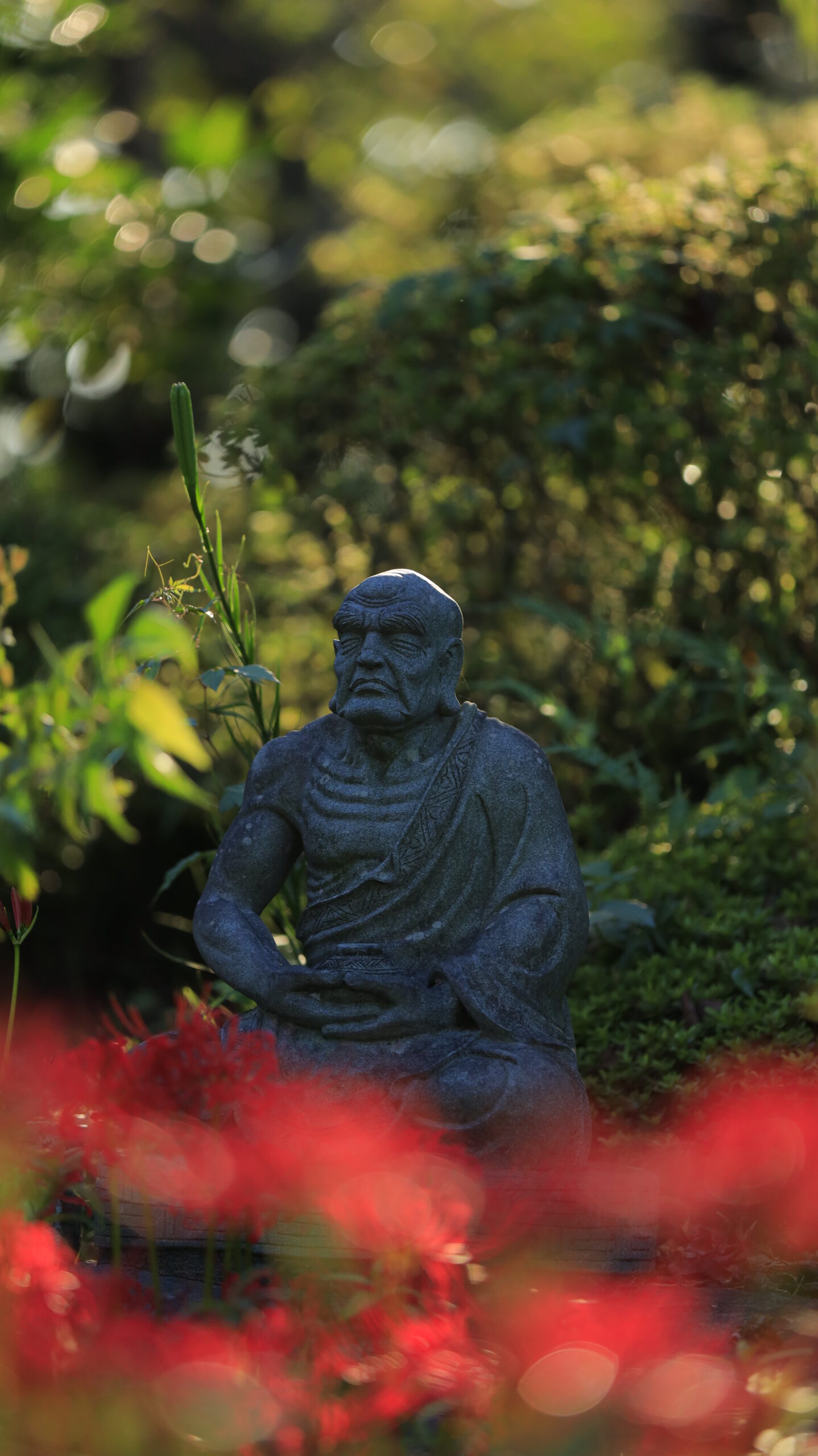常楽寺で、力強い石像とその下に咲く彼岸花を組み合わせ奥行きを意識して撮影した写真
